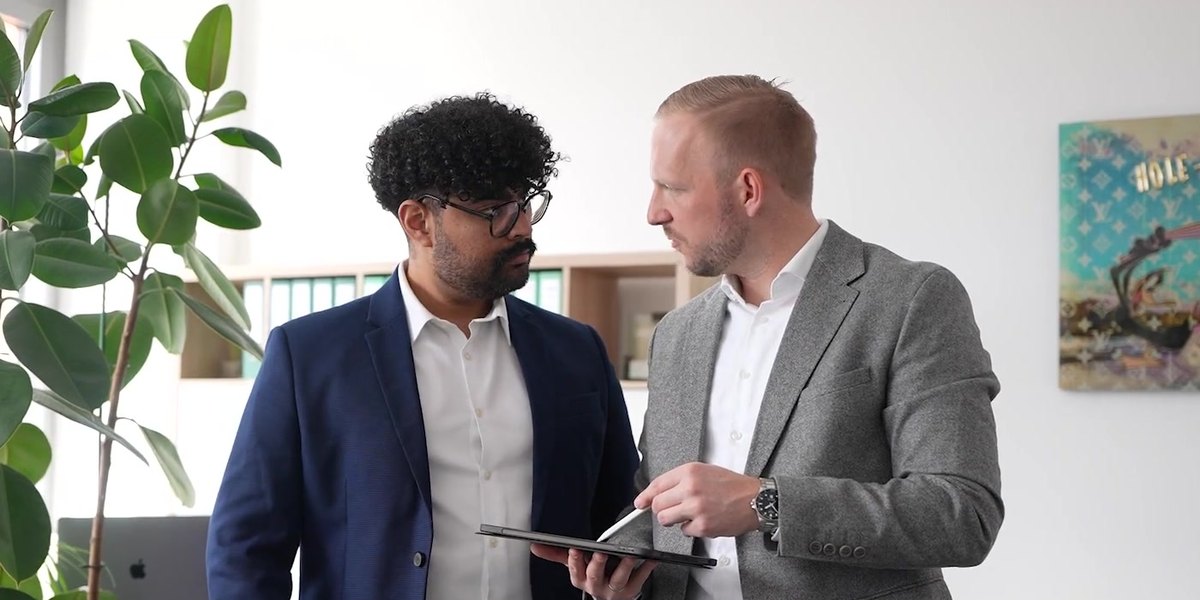 Zwei Berater von CODE FINANCE besprechen im Büro in Karlsruhe Unterlagen auf einem Tablet